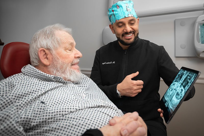 patient smiling brightly while doctor is going over dental procedure information with x-ray scans
