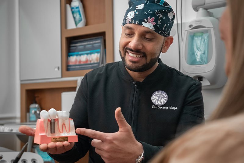 Doctor Surdeep Singh showing patient dental implant model